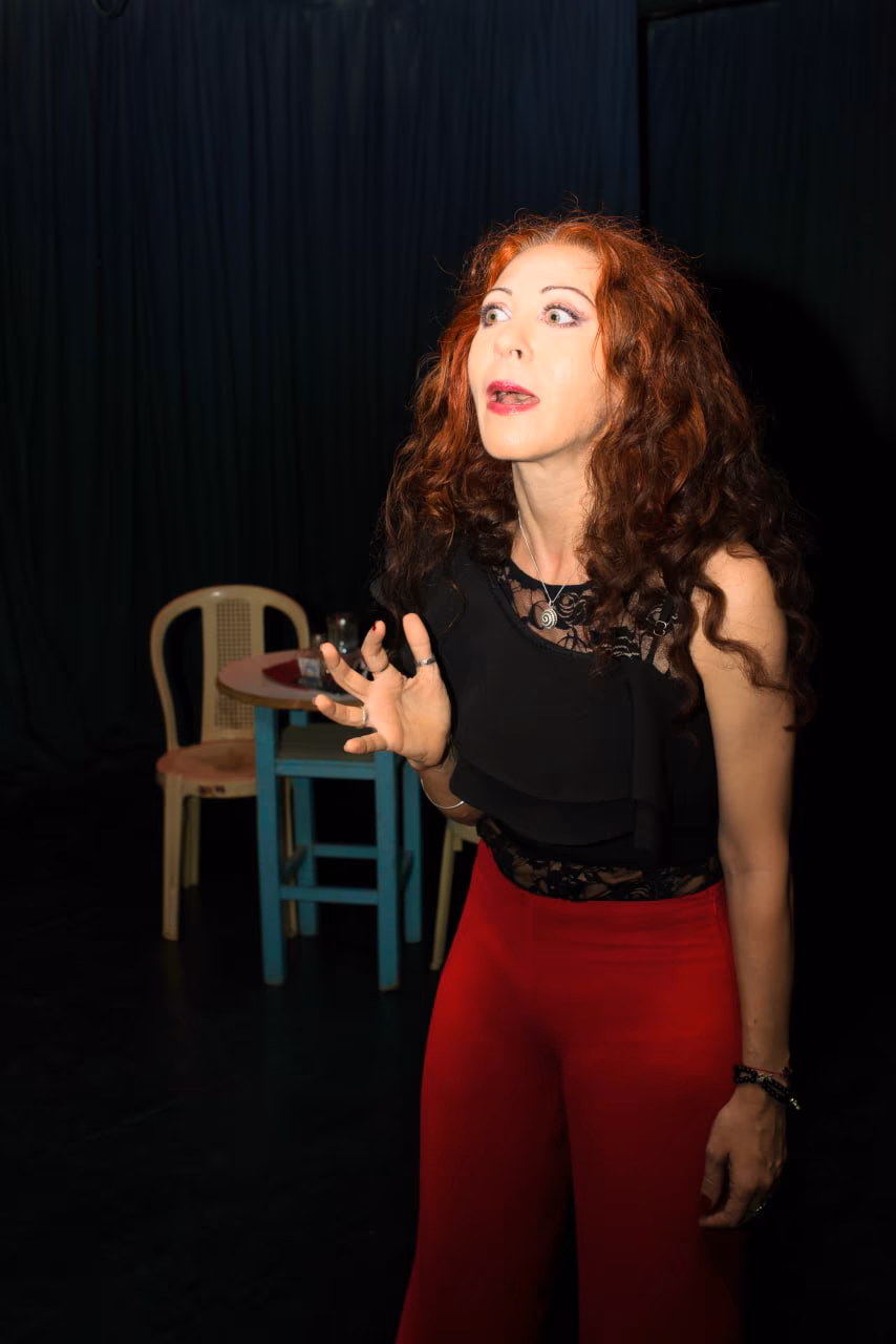 Eva ArtVision en un momento actoral, expresión sorprendida y gesto con la mano, en escena de teatro